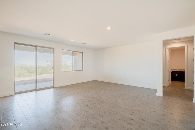 unfurnished room featuring recessed lighting, wood finished floors, visible vents, and baseboards