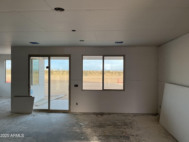 spare room featuring a healthy amount of sunlight and unfinished concrete flooring