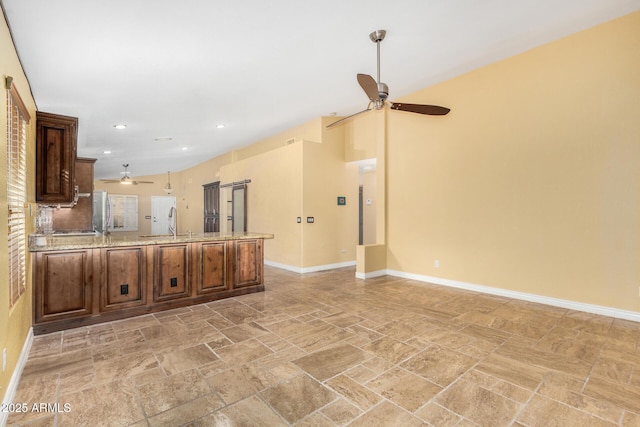 unfurnished living room featuring a ceiling fan, a sink, baseboards, stone tile flooring, and recessed lighting
