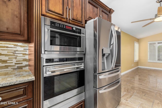 kitchen with ceiling fan, appliances with stainless steel finishes, baseboards, decorative backsplash, and vaulted ceiling