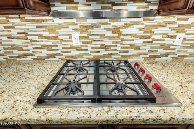 room details with tasteful backsplash, stainless steel gas cooktop, and light stone countertops