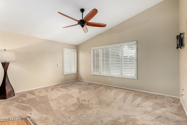 carpeted empty room with a ceiling fan, baseboards, and vaulted ceiling
