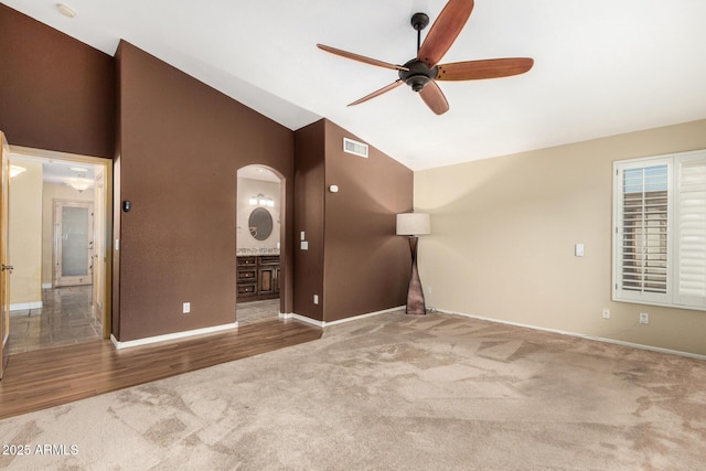 unfurnished living room with visible vents, baseboards, ceiling fan, arched walkways, and carpet flooring