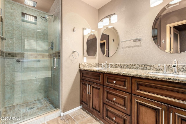 bathroom with a sink, baseboards, a stall shower, and double vanity