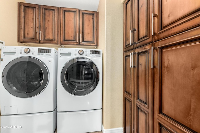 clothes washing area featuring cabinet space and washer and dryer