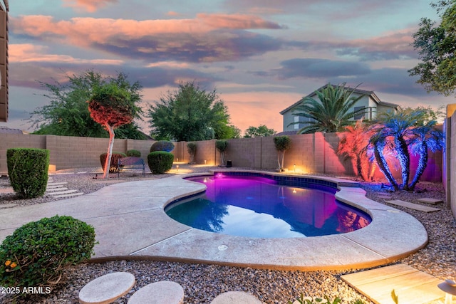 pool at dusk featuring a fenced in pool, a fenced backyard, and a patio