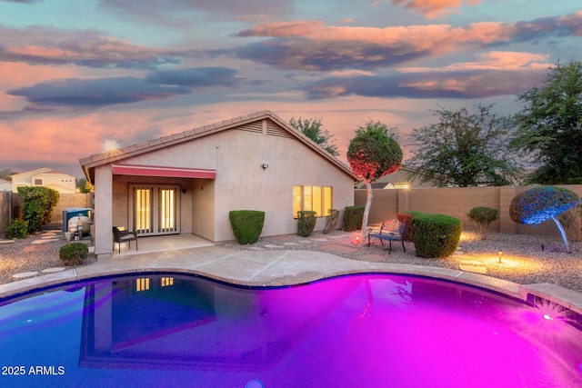 pool at dusk with a fenced in pool, french doors, a fenced backyard, and a patio area