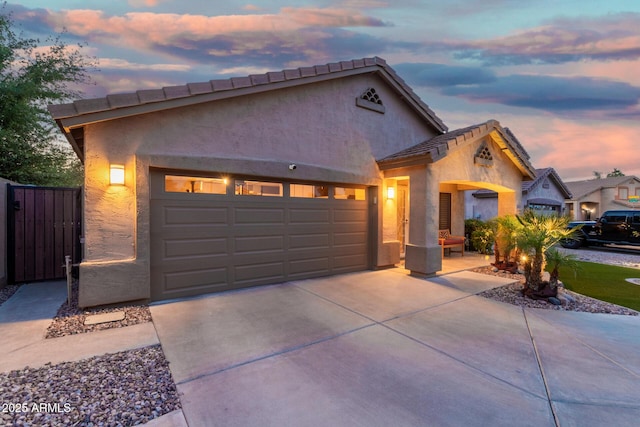 view of front facade featuring a garage, stucco siding, concrete driveway, and a tiled roof