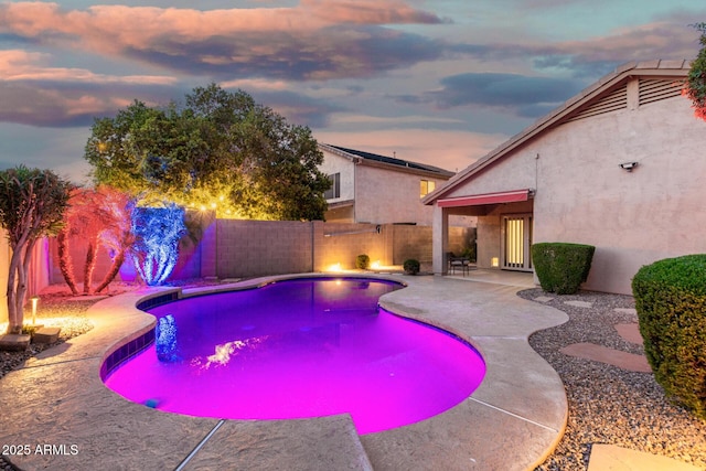 pool at dusk with a fenced backyard, a fenced in pool, and a patio