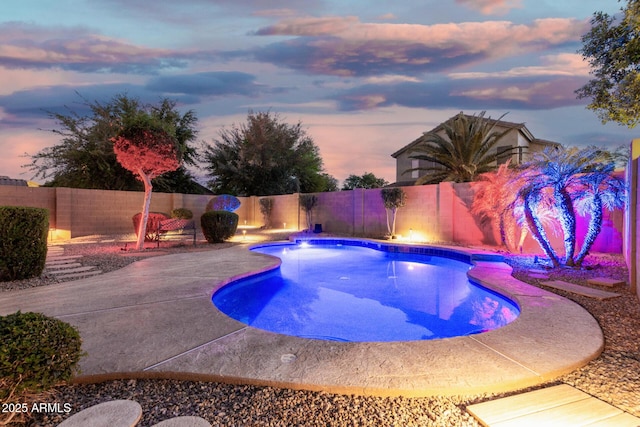 pool at dusk with a patio, a fenced in pool, and a fenced backyard
