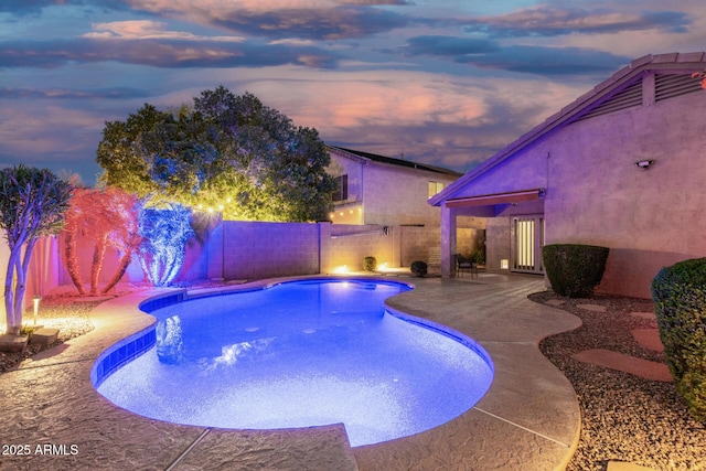 pool at dusk with a patio, a fenced in pool, and a fenced backyard
