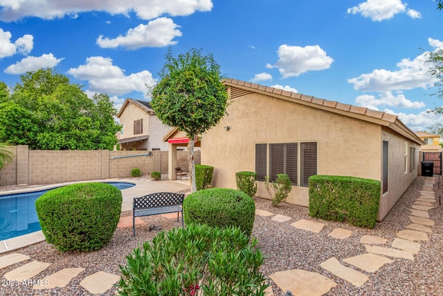 back of house with a patio, a fenced in pool, a fenced backyard, and stucco siding