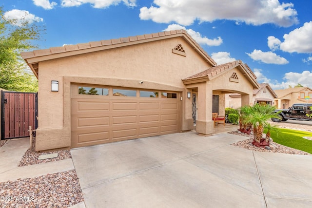 view of front of home featuring a tile roof, a garage, fence, concrete driveway, and stucco siding
