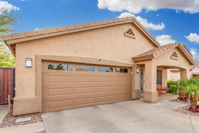 view of front of home featuring an attached garage, stucco siding, fence, and concrete driveway