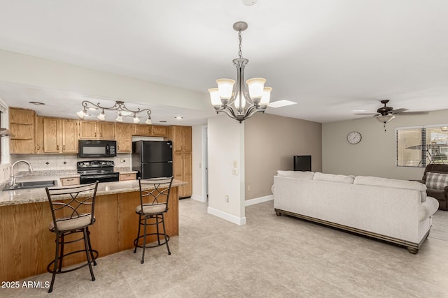 kitchen featuring sink, a breakfast bar, tasteful backsplash, black appliances, and decorative light fixtures