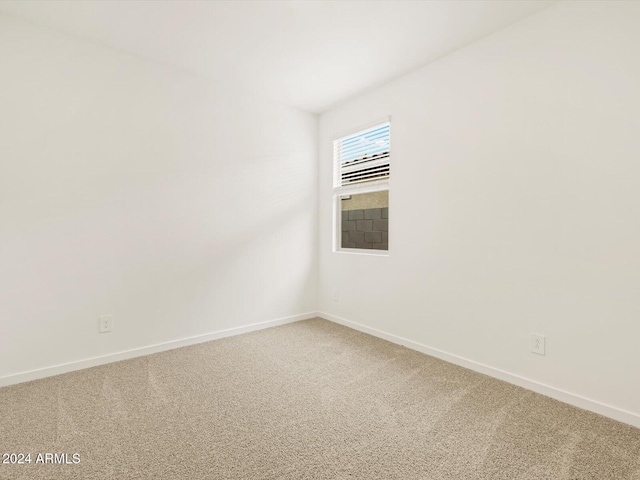 empty room featuring light colored carpet and baseboards