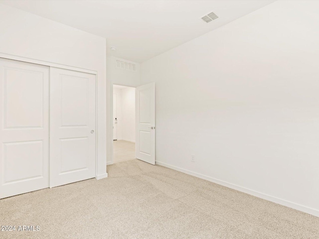 unfurnished bedroom featuring baseboards, visible vents, carpet floors, and a closet