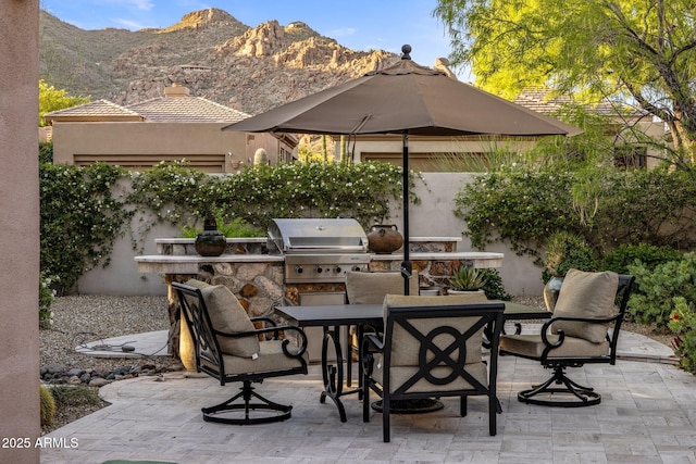 view of patio with grilling area, outdoor dining space, an outdoor kitchen, and a mountain view