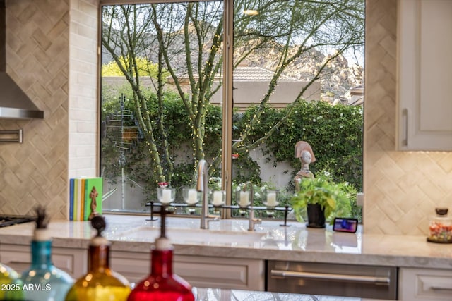 exterior space with decorative backsplash, stainless steel dishwasher, and wall chimney range hood