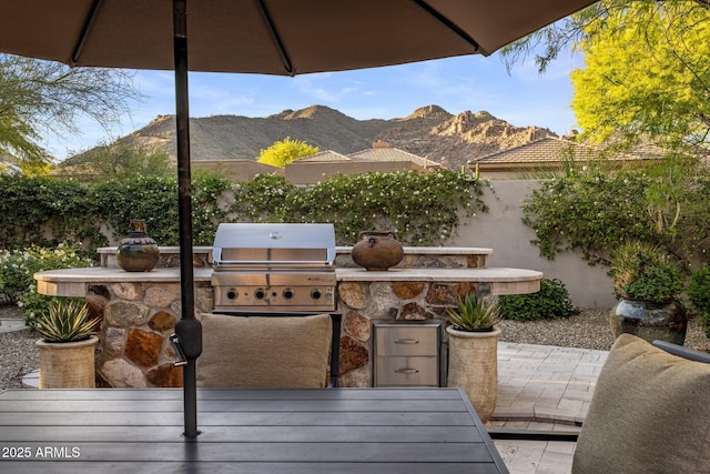 view of patio / terrace featuring grilling area, exterior kitchen, a mountain view, and fence