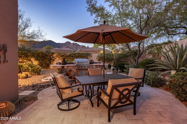 view of patio with outdoor dining space, area for grilling, a mountain view, a grill, and a fenced backyard