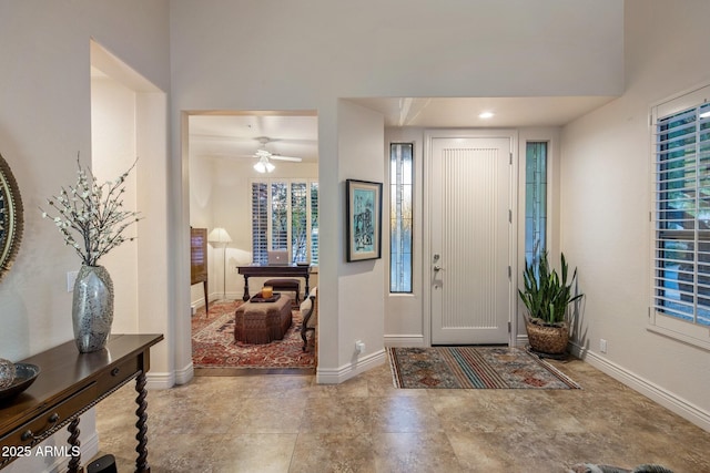 foyer with baseboards and ceiling fan