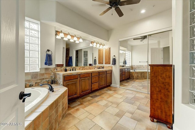 bathroom with tiled bath, vanity, and ceiling fan