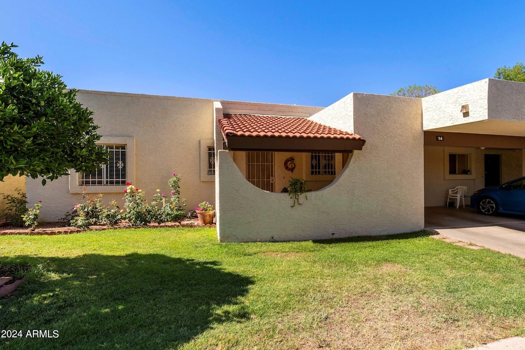 pueblo revival-style home with a carport and a front lawn