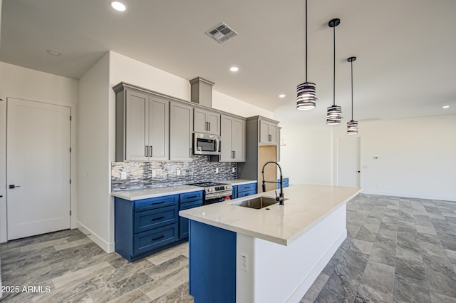 kitchen featuring a center island with sink, appliances with stainless steel finishes, sink, backsplash, and pendant lighting