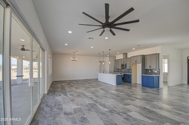 unfurnished living room featuring ceiling fan with notable chandelier and sink