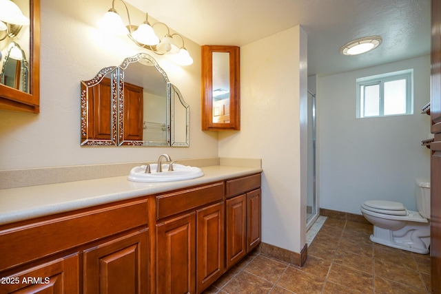 bathroom featuring a shower stall, toilet, vanity, and baseboards