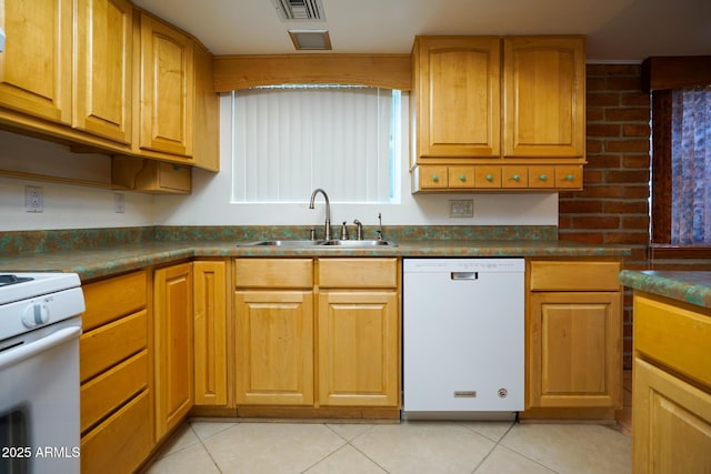 kitchen with a sink, white appliances, dark countertops, and light tile patterned floors