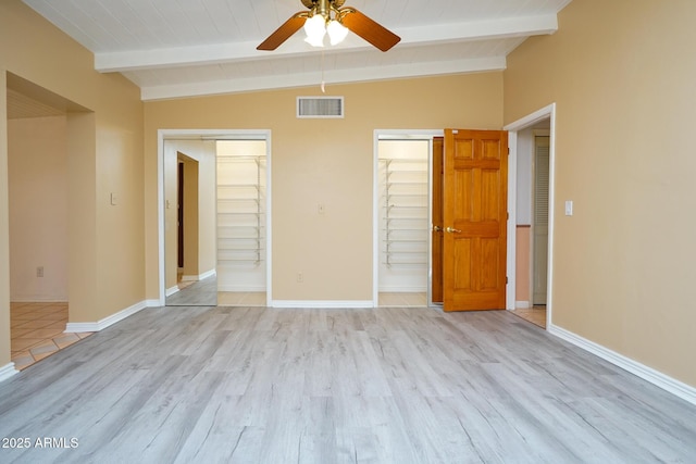 unfurnished bedroom featuring visible vents, baseboards, and vaulted ceiling with beams