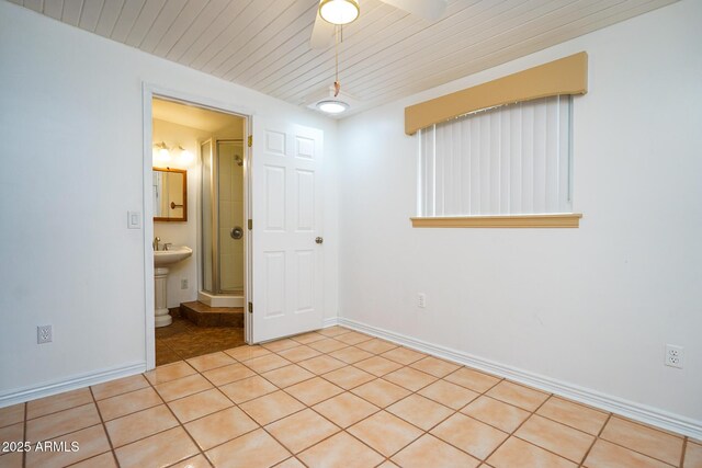 empty room featuring light tile patterned floors, baseboards, wooden ceiling, and a ceiling fan