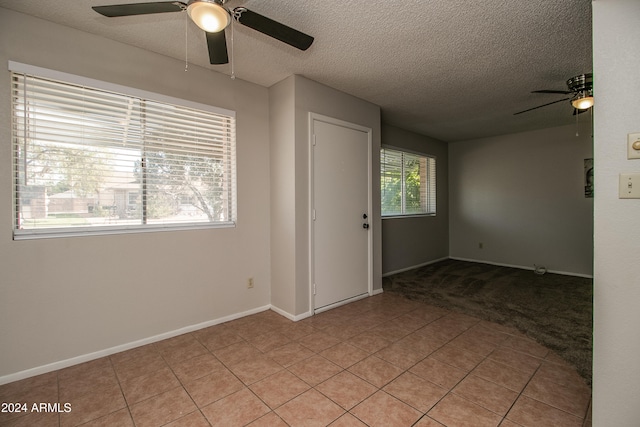 tiled empty room with ceiling fan and a textured ceiling