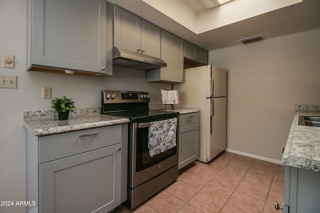 kitchen with gray cabinets, stainless steel electric range oven, light tile patterned floors, and white fridge