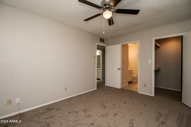 unfurnished bedroom featuring a textured ceiling, ceiling fan, light carpet, and connected bathroom