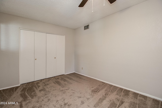 unfurnished bedroom featuring a textured ceiling, carpet floors, a closet, and ceiling fan