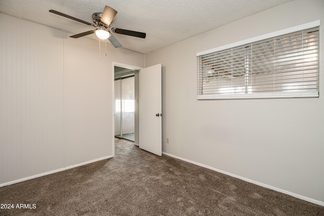 carpeted spare room with ceiling fan, a textured ceiling, and a wealth of natural light