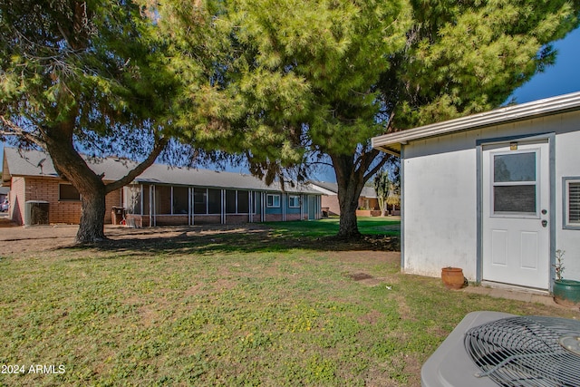 view of yard featuring a sunroom and central air condition unit