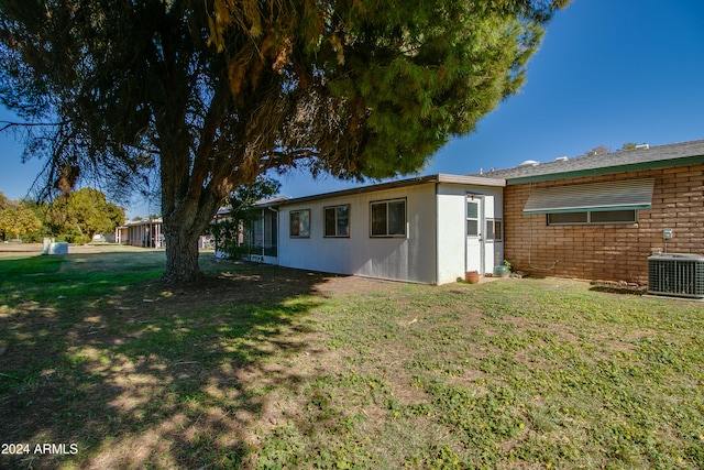 rear view of house featuring cooling unit and a yard