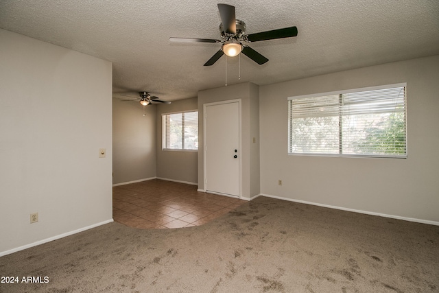 unfurnished room featuring a textured ceiling, dark carpet, and ceiling fan