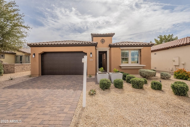 mediterranean / spanish-style house featuring fence, a tiled roof, stucco siding, decorative driveway, and a garage