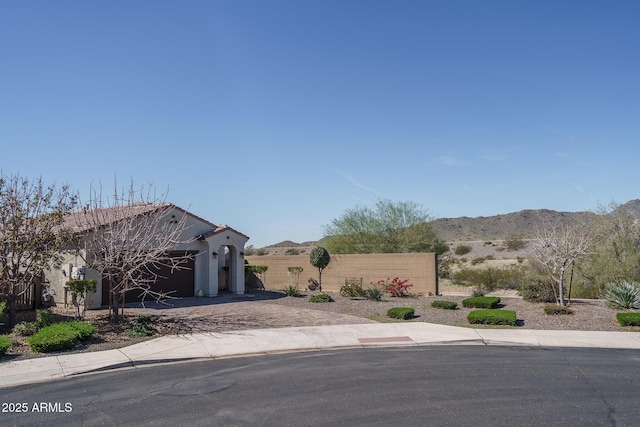 exterior space with a garage, driveway, fence, and a mountain view