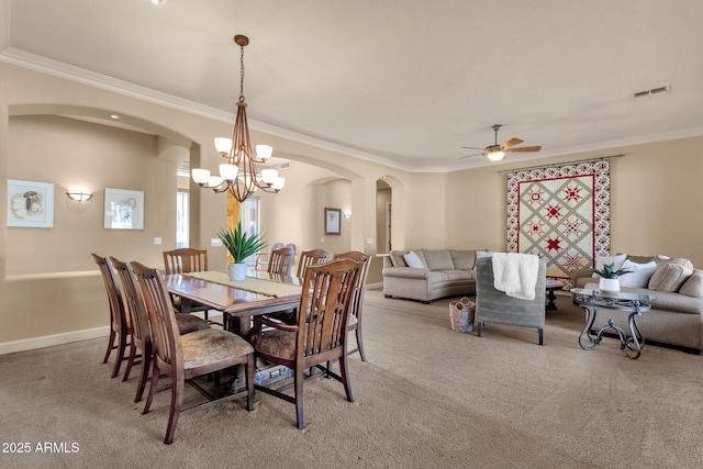 carpeted dining area with ceiling fan with notable chandelier and ornamental molding