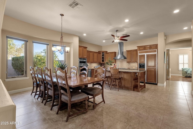 tiled dining space featuring sink and ceiling fan with notable chandelier