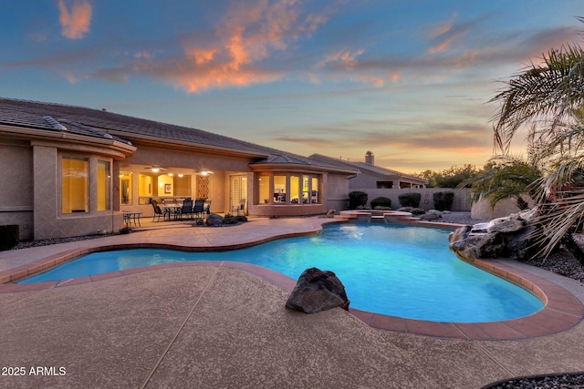 pool at dusk featuring a patio area