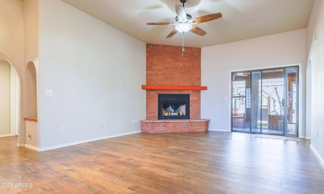 unfurnished living room featuring ceiling fan, hardwood / wood-style floors, and a brick fireplace