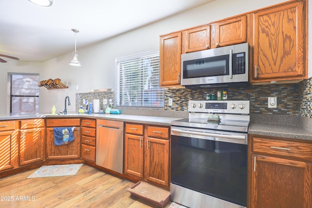 kitchen with stainless steel appliances, plenty of natural light, decorative backsplash, and light hardwood / wood-style flooring