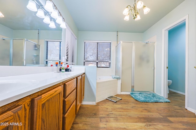 full bathroom featuring hardwood / wood-style floors, a chandelier, separate shower and tub, vanity, and toilet